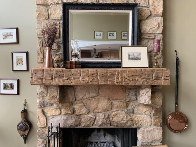 Hand hewn reclaimed barnwood mantel on hearth